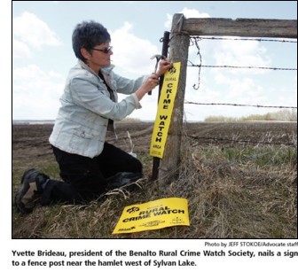 Yvette Brideau, president of the Benalto Rural Crime Watch Society, nails a sign to a fencepost near the hamlet west of Sylvan Lake Alberta.